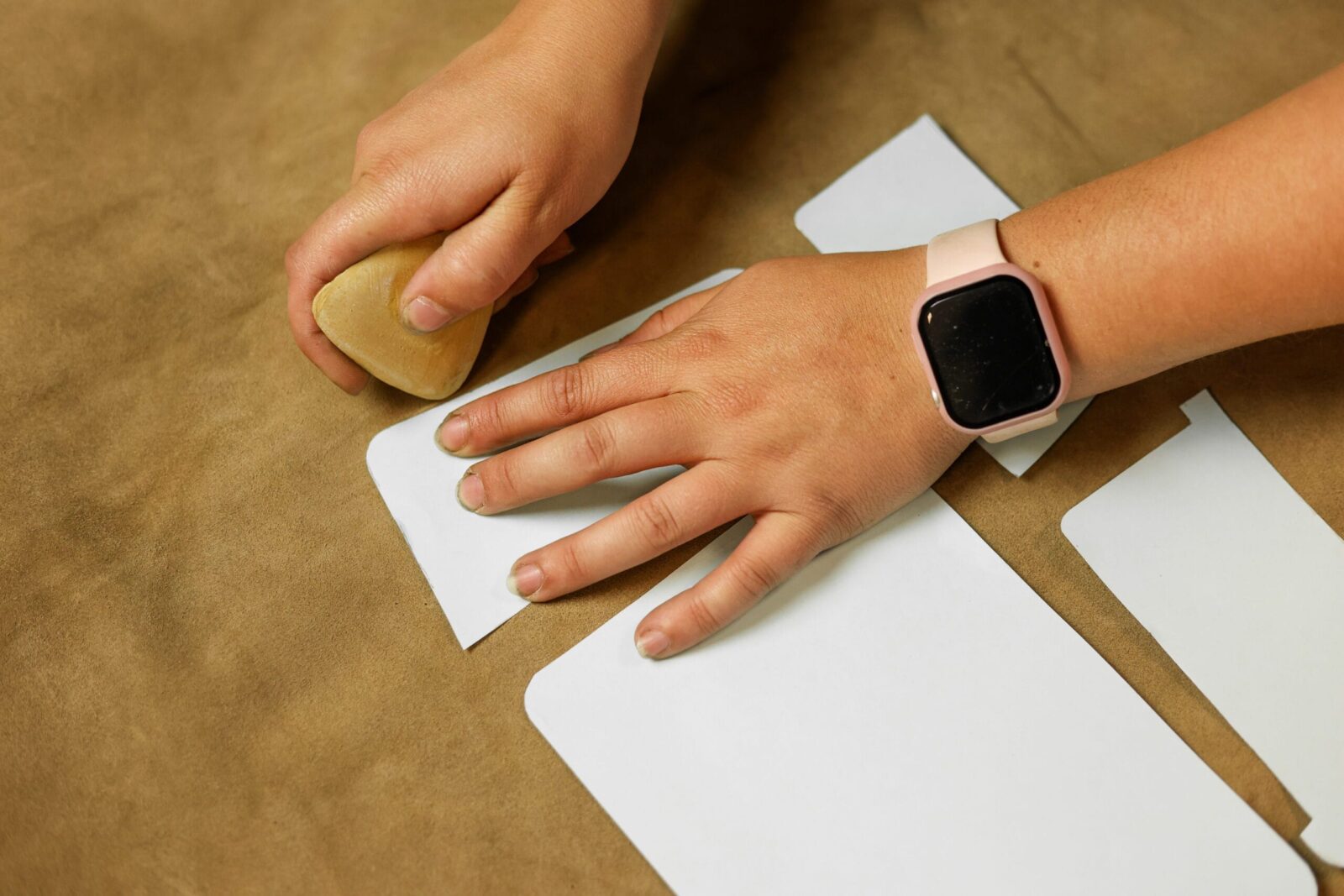 Hand tekent een patroon af op een stuk leer met behulp van een mal.